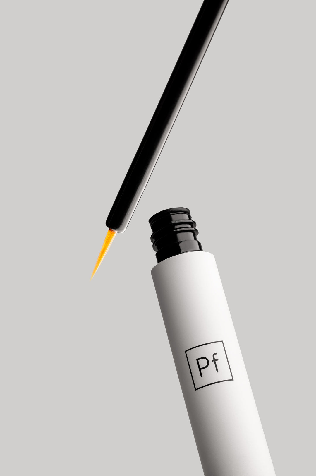 Ultraboost lash and brow serum tube opened, applicator tip angled in from the top right, minimal styled shot